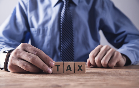 Businessman holding wooden cube with Tax word.の写真素材
