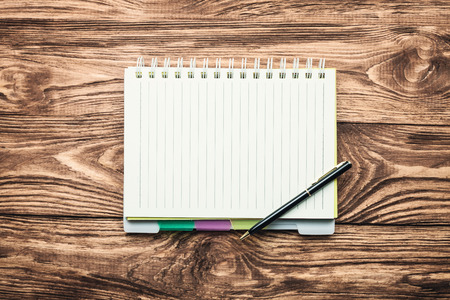 Pen and notepad on a wood background.の写真素材