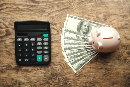 Piggy bank with money and calculator on wooden desk. Save your moneyの写真素材