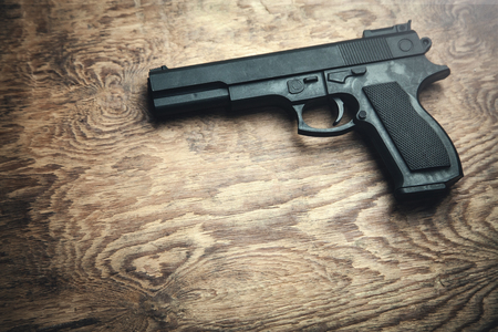 Pistol on wooden background.