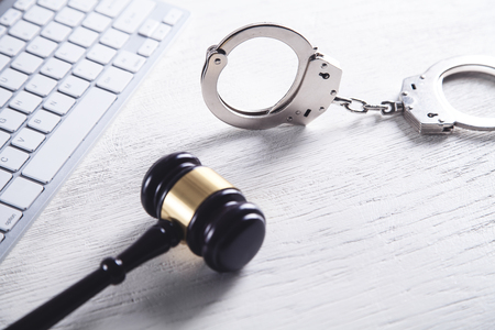 Handcuffs and Judge Gavel with computer keyboard. Concept of  Cyber crime and Online fraudの写真素材