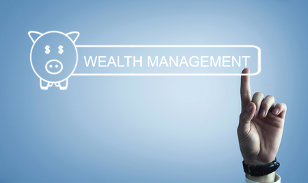 Hand pressing in Wealth management text with a piggy bank.の写真素材