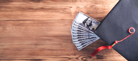 Graduation hat and money on wooden table.の写真素材