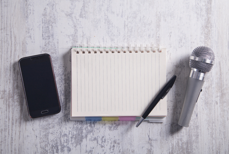 Microphone, smartphone, notepad and pen on the modern desk.の写真素材
