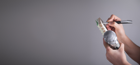 Hands holding microphone and writing on notepad.の写真素材