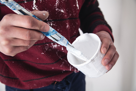 Man hands paintbrush with white paint. Renovationの写真素材