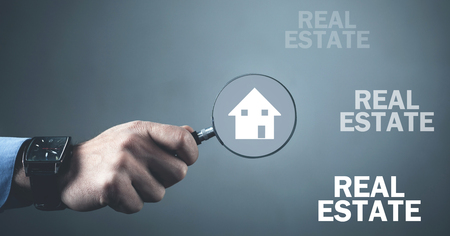 Man holding magnifier with house icon. Real estateの写真素材