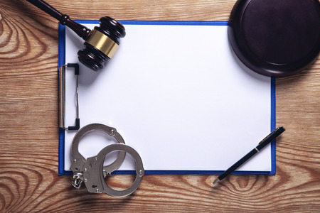 Clipboard, handcuffs, pen with judge gavel on wooden background.の写真素材