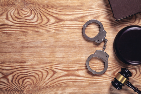 Metal handcuffs and judge gavel on wooden background. Crime and Law Conceptの写真素材