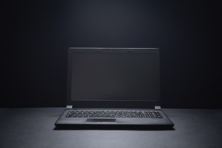 Black laptop on the black office desk. Technology conceptの写真素材