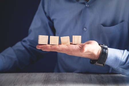 Businessman holding wooden cube on a wooden table.の写真素材