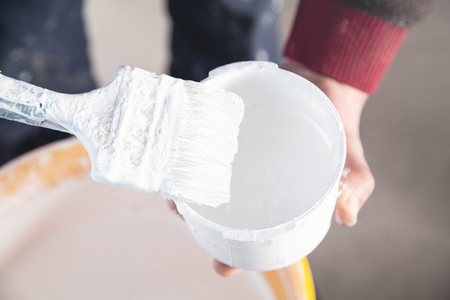 Man hands paintbrush with white paint. Renovationの写真素材
