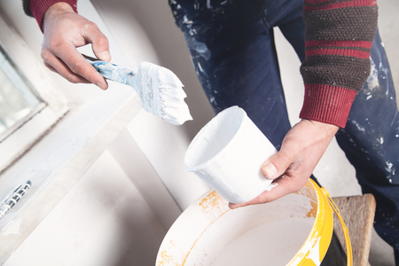 Man hands paintbrush with white paint. Renovationの写真素材