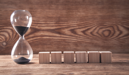 Hourglass with wooden cubes on wooden background.の写真素材