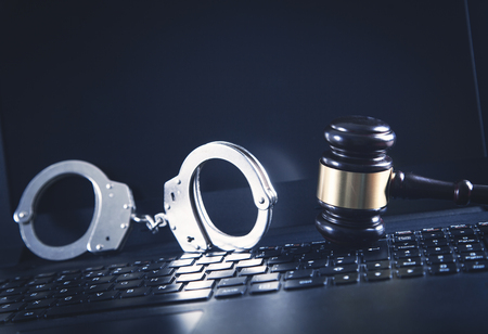 Handcuffs and Judge Gavel on laptop keyboard. Concept of  Cyber crime and Online fraud