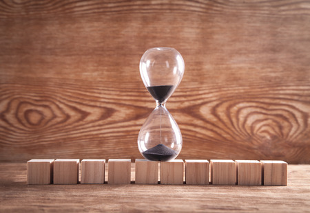 Hourglass with wooden cubes on wooden background.の写真素材