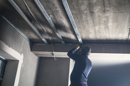 Working with a metal profile of a ceiling construction.の写真素材