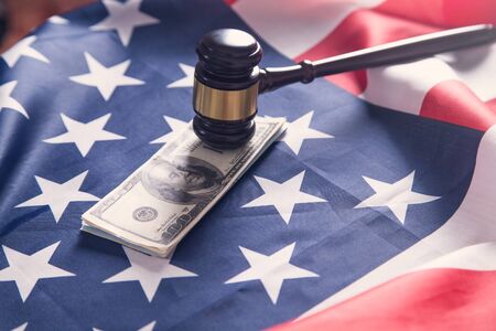 Judge gavel with dollars and American flag.