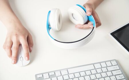 Hand holding headphones in office desk. Listening music