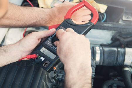 Mechanic with a multimeter testing car engine. Car service