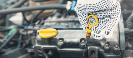 Auto mechanic checking the car engine oil level.