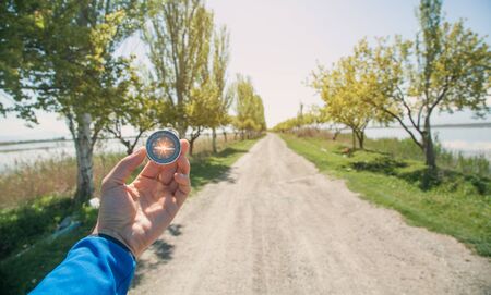 Traveler holding compass in road background.