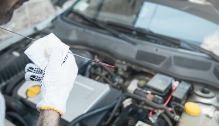Technician checking oil level in car engine.