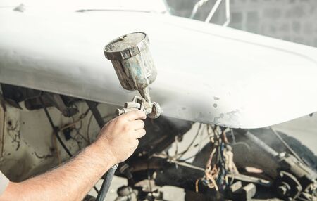 Spray gun in the hand of a painter. Painting car detailsの写真素材