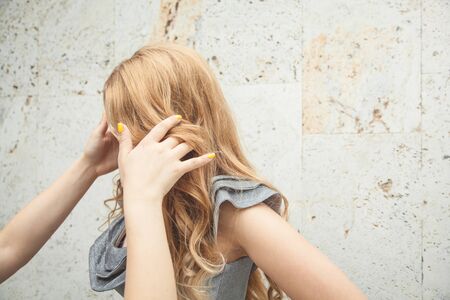 Woman makes evening hairstyle to the blond model.の写真素材