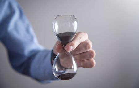 Businessman holding hourglass. Deadline concept