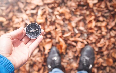 Man holding compass in autumn forest.の写真素材