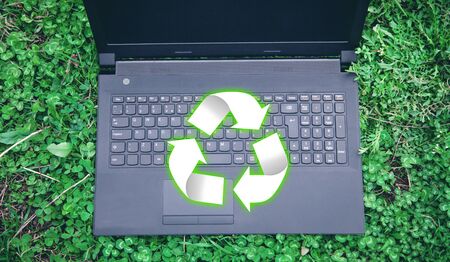 Black laptop with Recycle sign in the grass.の写真素材