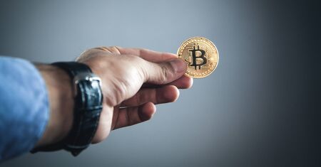 Male hand holding golden bitcoin. Virtual money concept
