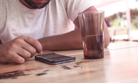 Man using smartphone sitting in cafe.
