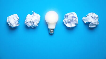 Light bulb and crumpled papers in the blue background. Idea