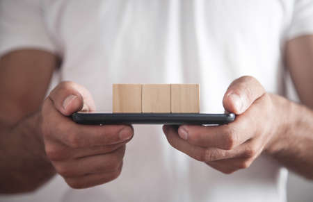 Man holding smartphone with empty wooden cubes.