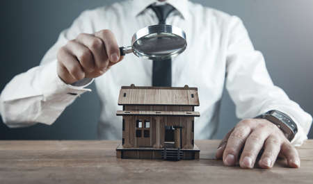 Man magnifying wooden house model. Home inspectionの写真素材