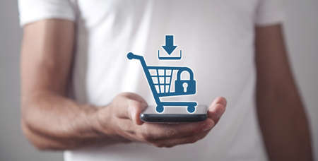 Businessman holding a phone with a shopping cart. Shopping security. Online shopping