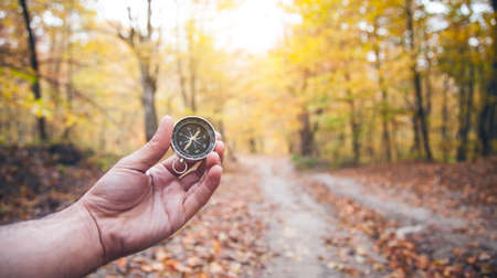 Male hand holding compass in autumn forest.の写真素材