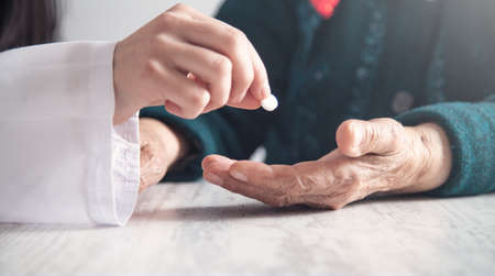 Doctor giving pill to elderly woman. Health, Medicine, Careの写真素材