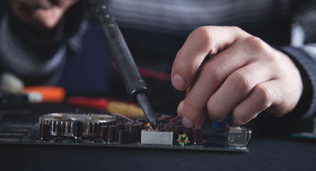Computer hardware engineering. Engineer soldering computer motherboard