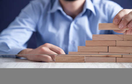 Man stacking wooden blocks. Development conceptの写真素材