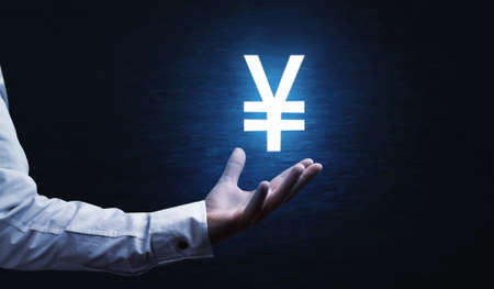 Male hand holding yen currency symbol.の写真素材