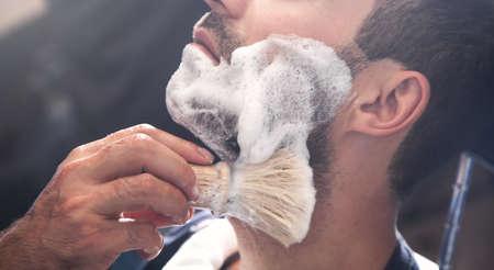Hairdresser applying cream for shaving.の写真素材