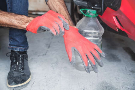 Man wearing red protective gloves in garage.の写真素材