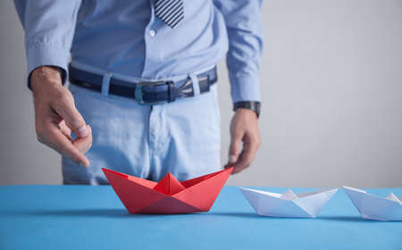 Businessman in office. Red origami paper boat with a white boats. Business, Leadershipの写真素材