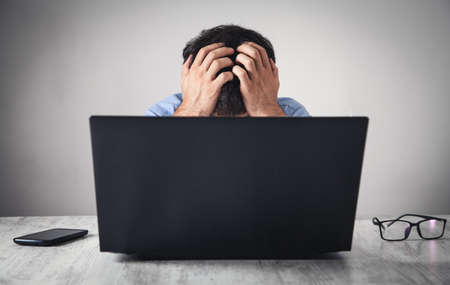 Caucasian stressed businessman sitting and covering face in office.の写真素材