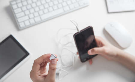 Hands holding earphones and smartphone in office.の写真素材