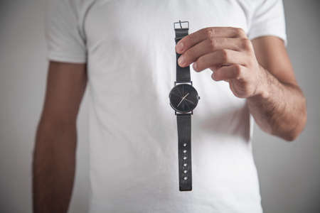 Caucasian man holding wrist watch in office.