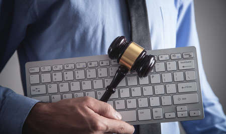 Man holding Judge gavel with computer keyboard. Concept of internet crimeの写真素材